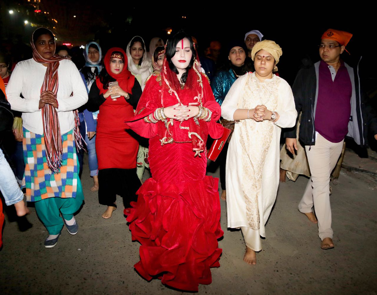 radhe-maa-in-a-red-mermaid-outfit-replete-with-a-red-purse-and-surrounded-by-devotees